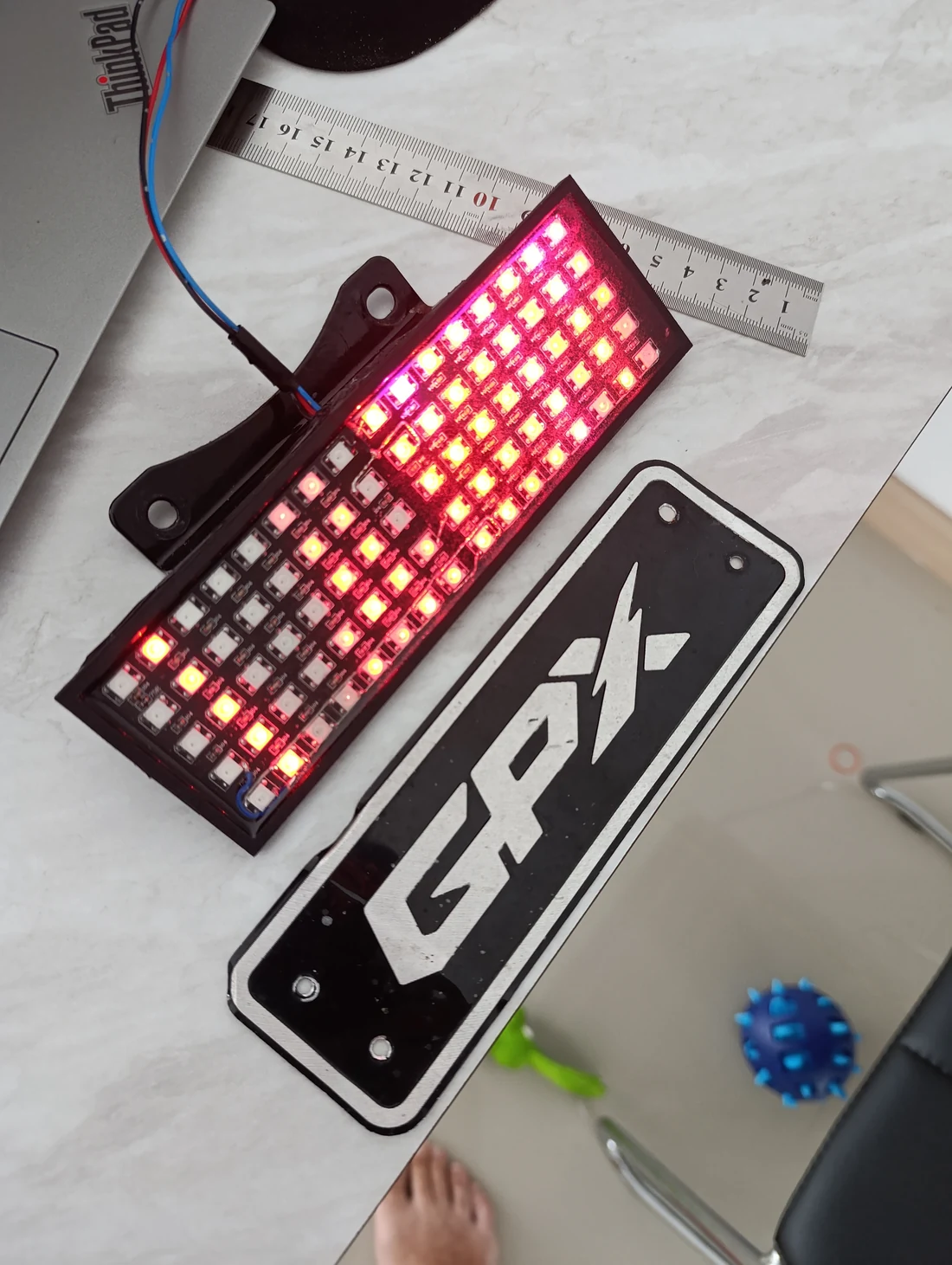 Rectangular RGB LED display powered up in its mounting frame on the workbench