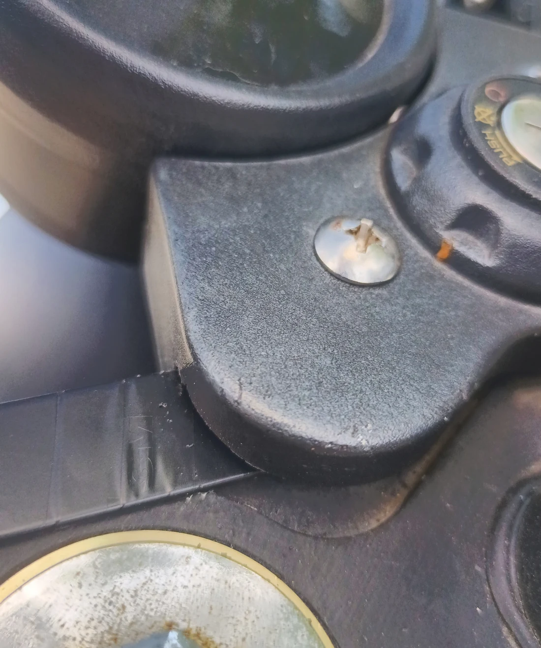 Close-up of the ignition-switch cover filed for clearance around the tape-wrapped windscreen bracket